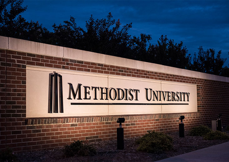 Methodist University sign lit up after dark