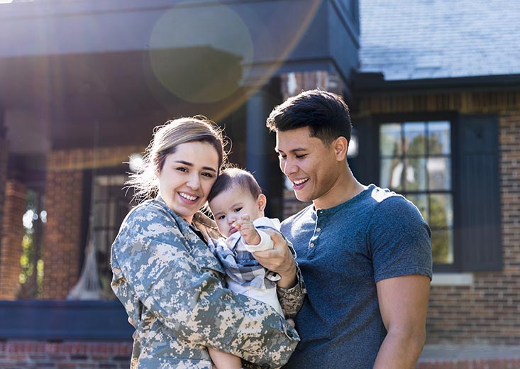 woman in military uniform holding child standing by partner