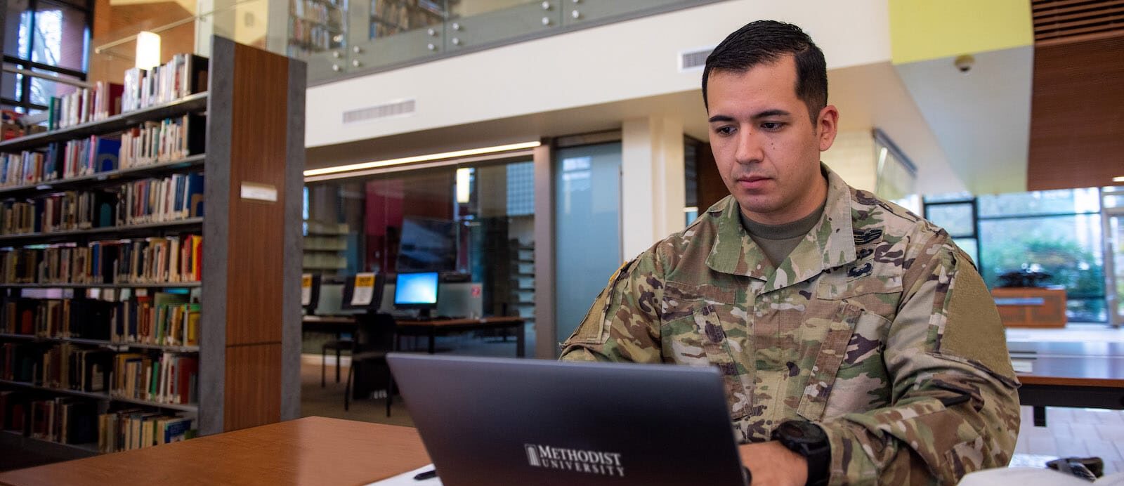 man in uniform working on laptop in library